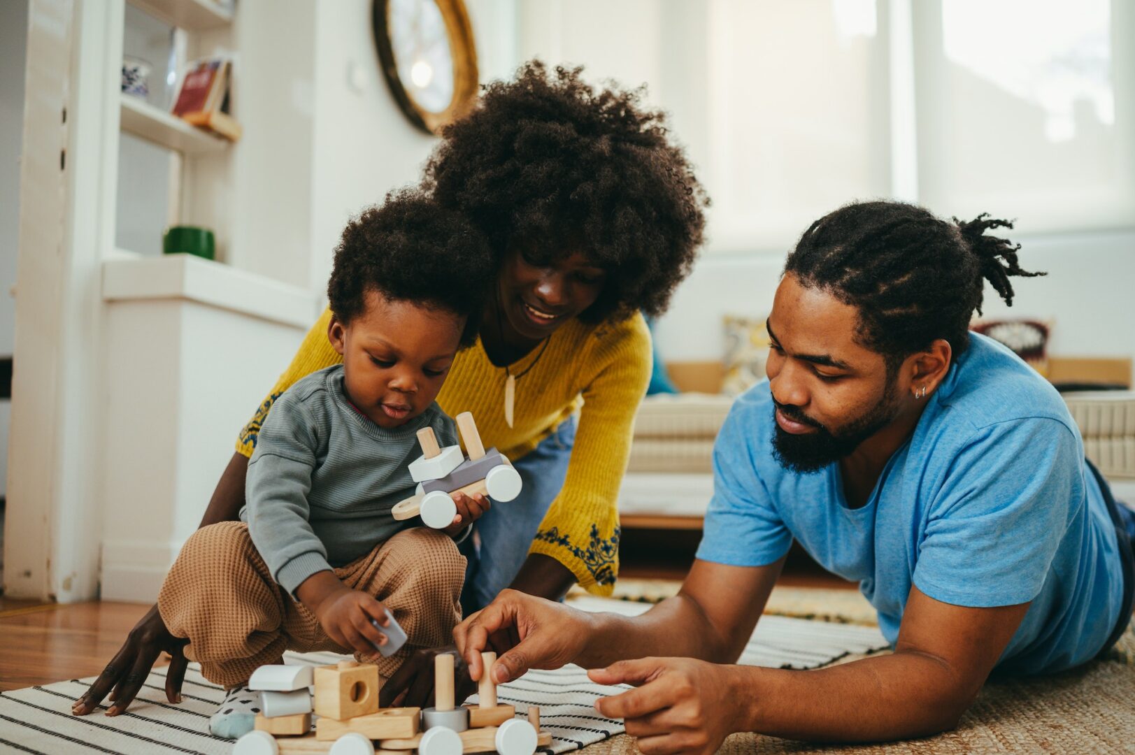 An african american kid is playing with his parents and learning shapes and colors through the game.